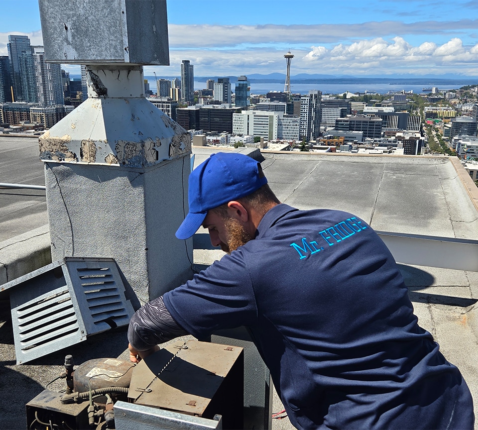 Fridge Repair Technician is Performing Maintenance on HVAC, Fridge System with Down town Seattle on background.