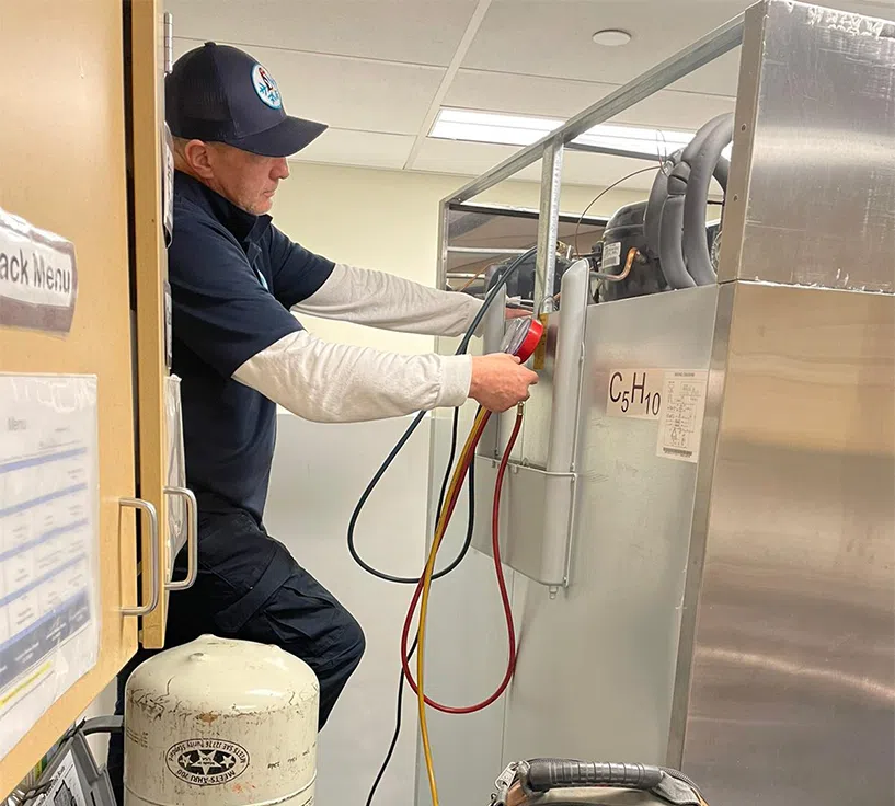 Mr. Fridge technician performing diagnostics on a commercial freezer unit.